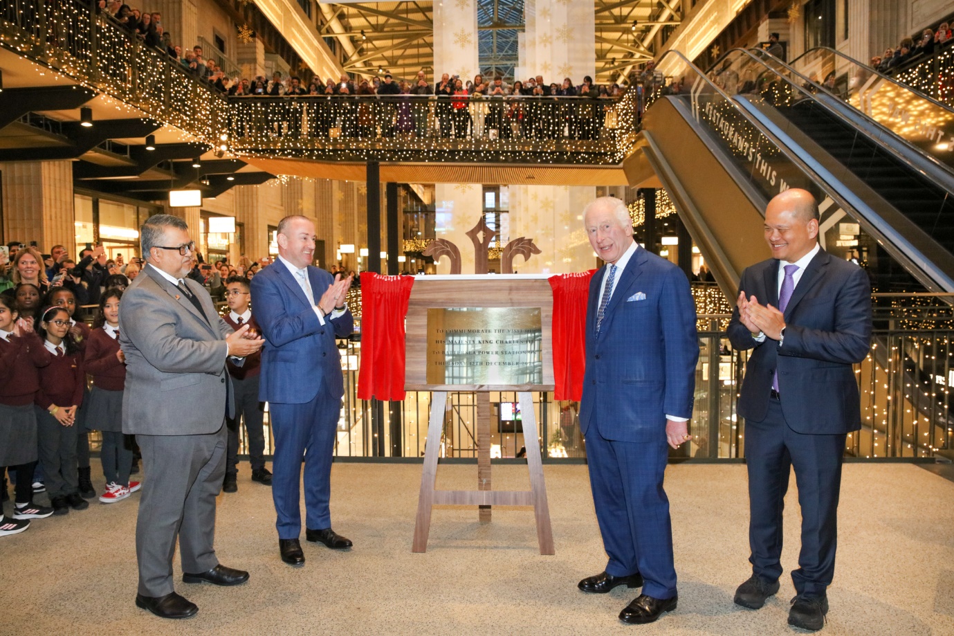 A group of men standing in a room with a display caseDescription automatically generated